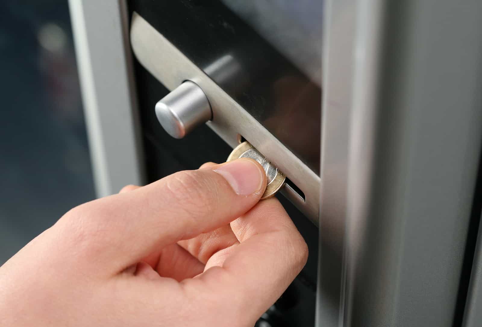 a person inserting a coin into a vending machine